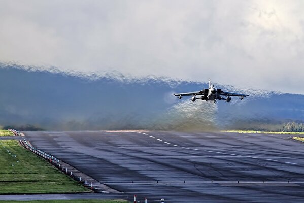 A fighter jet takes off over the runway. The air melts