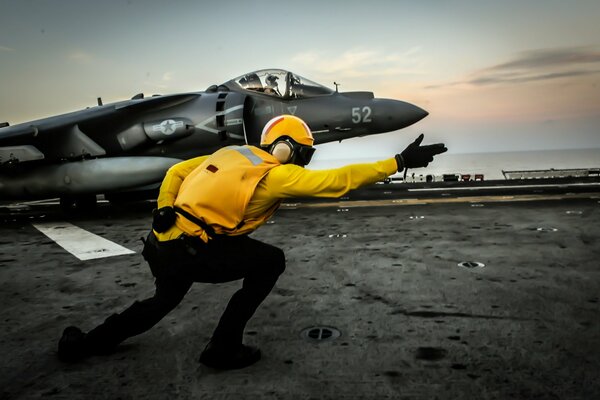 Traffic controller and fighter on an aircraft carrier at sea