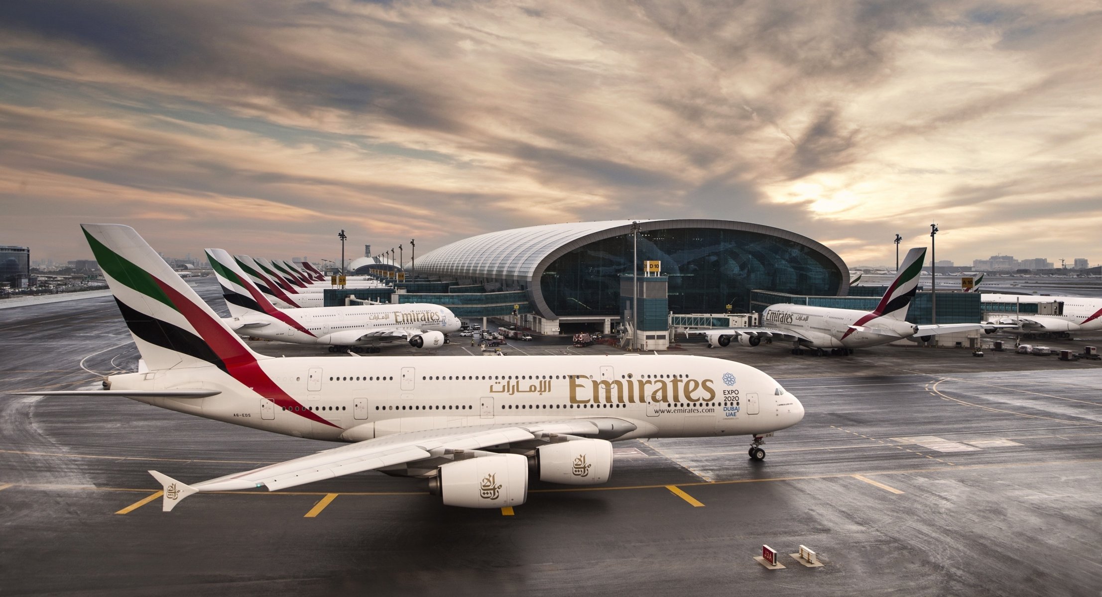 línea aérea de emirates airbus a380 avión avión pasajero aeropuerto dubai emiratos árabes unidos edificio terminal salida del sol cielo nubes pasajero