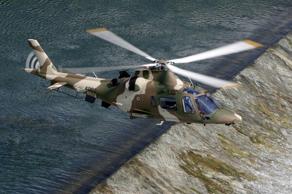 Italian agusta helicopter with camouflage paint, flying over the river