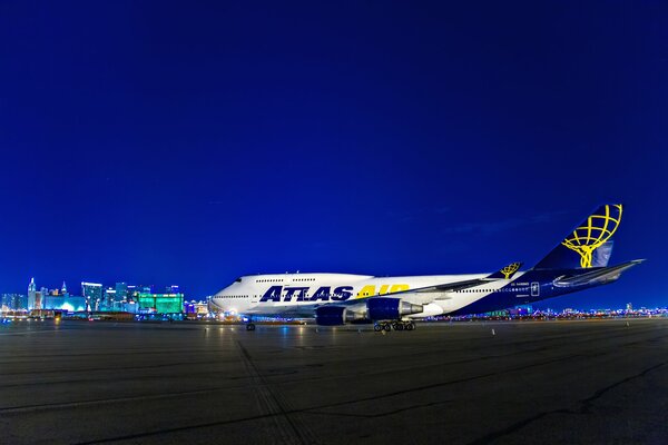 Junto a las luces de la noche en el aeropuerto de las Vegas en los Estados Unidos se encuentra un avión blanco y azul