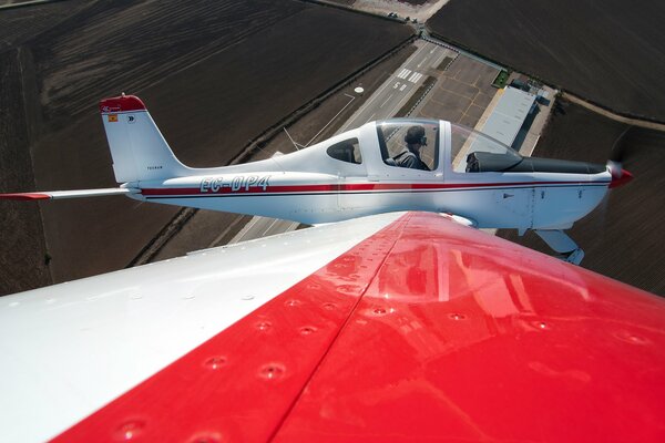 Vista desde el ala a un pequeño avión blanco y rojo