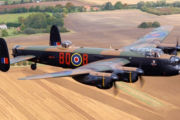 A bomber plane flies over the fields