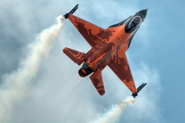 Multi-purpose fighter F-16 Fighting Falcon in red coloring on a blue sky background.