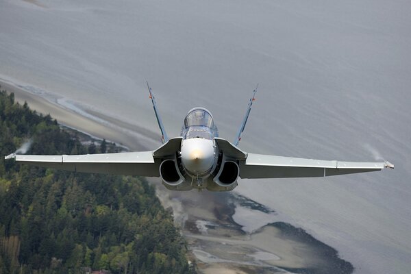 A multi-purpose military fighter is flying over the sea