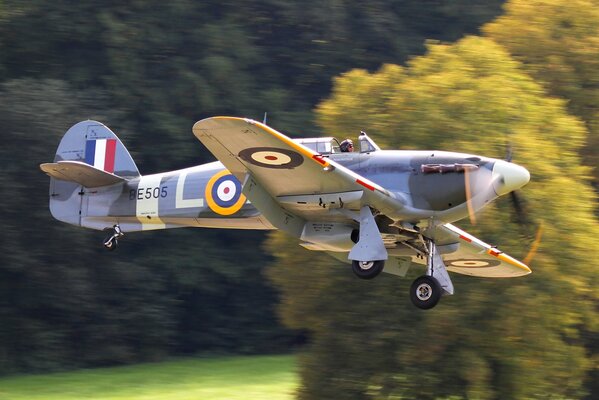 A single-seat British fighter, a hurricane, flies the French flag into the sky