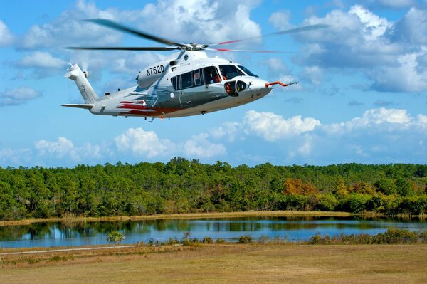 Un helicóptero vuela en medio de un lago y un bosque