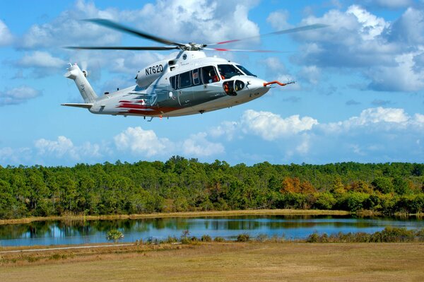 Helikopter leci na tle jeziora i lasu