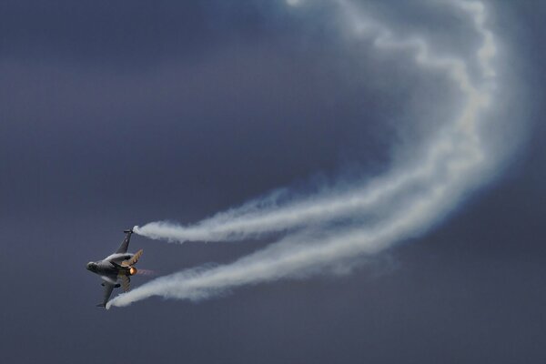 An airplane in the sky performs an aerobatic figure