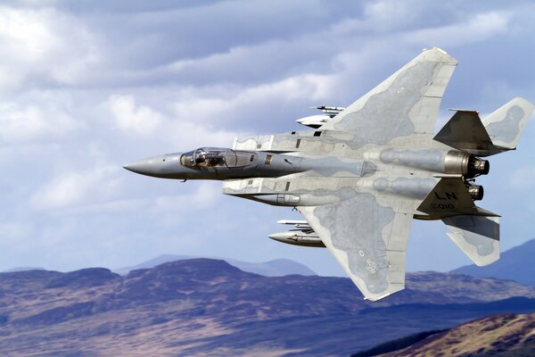 Military fighter plane in the sky over the mountains