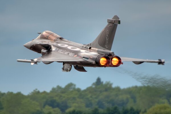 The take-off of the Rafale fighter over the forest