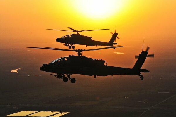 Un grupo de dos apache volando contra el sol