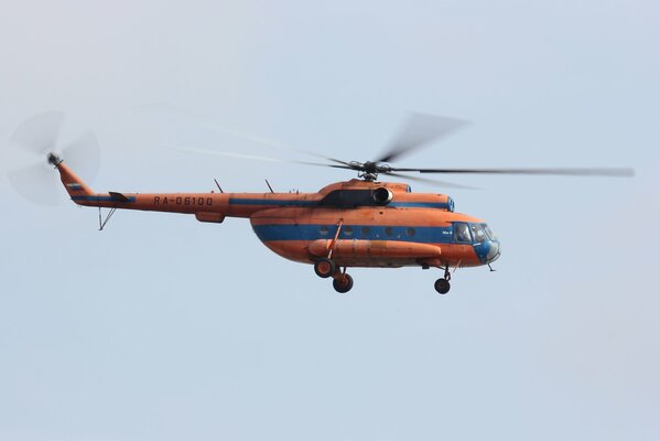 Российский многоцелевой вертолёт в оранжево-синей раскраске на фоне неба МИ-8 .