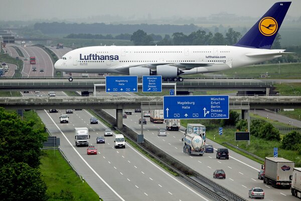 Un gran avión blanco vuela sobre una autopista