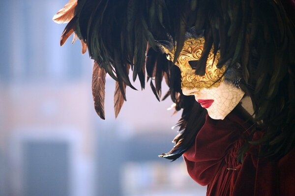 Венециаский карнавал. закрытая, красивая золотистая маска с перьями