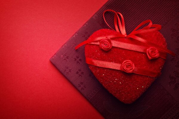 Red heart with roses on a background of burgundy fabric