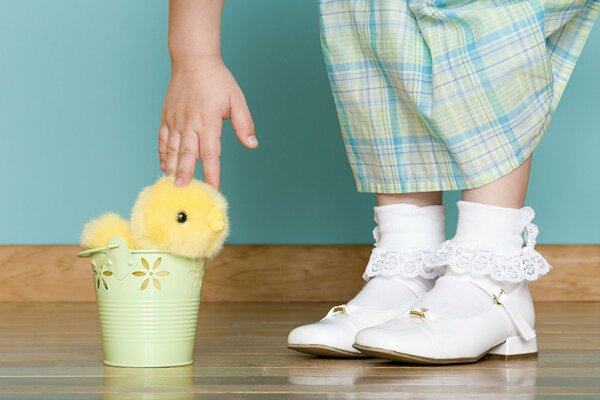 Ein Mädchen mit weißen Socken streckt sich zum Eimer