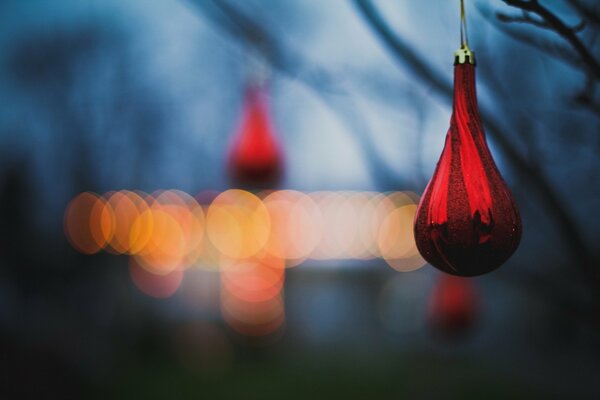 Rotes Tannenspielzeug vor dem Hintergrund von Lichtern