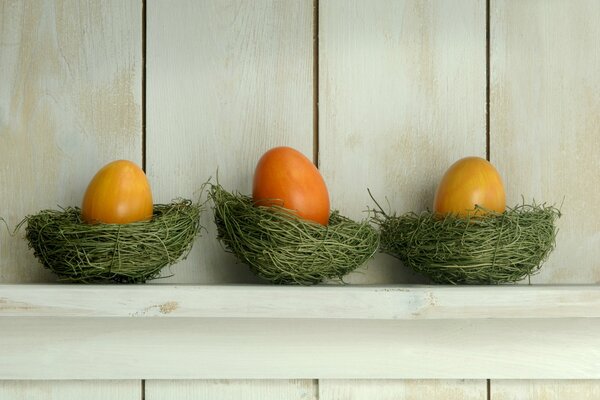 Three painted eggs in green nests