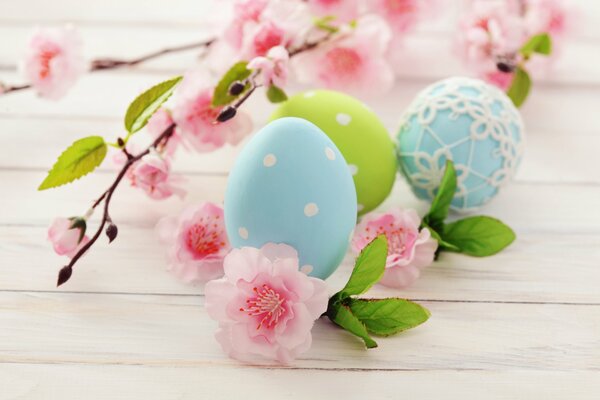 Oeufs de Pâques se trouvent à côté des fleurs roses