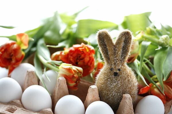 Conejito de Pascua entre flores y huevos