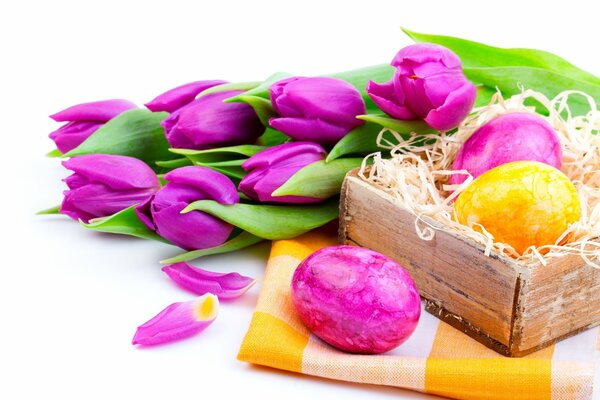 L uovo di Pasqua lilla e giallo si trova vicino ai tulipani