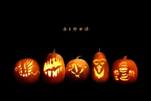 Pumpkins and different cutouts of muzzles on a black background