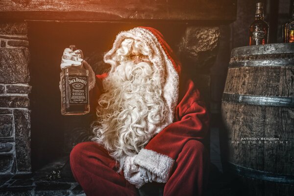 Le père Noël tient le whisky dans ses mains