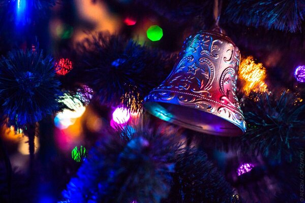 Ein Christbaumspielzeug in Form einer Glocke auf einem Zweig eines Weihnachtsbaums