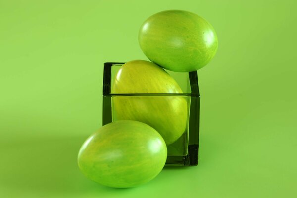 Пасхальные яйца на зелёном фоне со стаканом