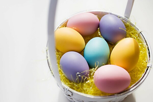 Huevos de Pascua pintados en una canasta sobre un fondo blanco