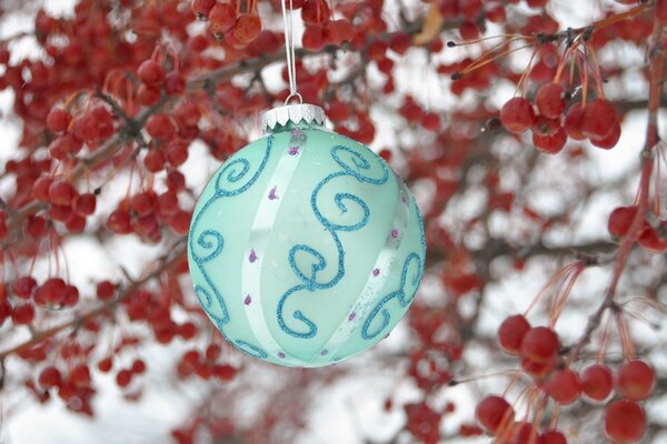 Albero di Natale, palla turchese su uno sfondo di bacche rosse