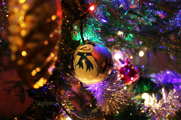 Muñeco de nieve en los rayos de las luces en el árbol de Navidad