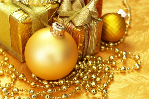 Goldener Weihnachtsschmuck und Geschenk mit Bogen