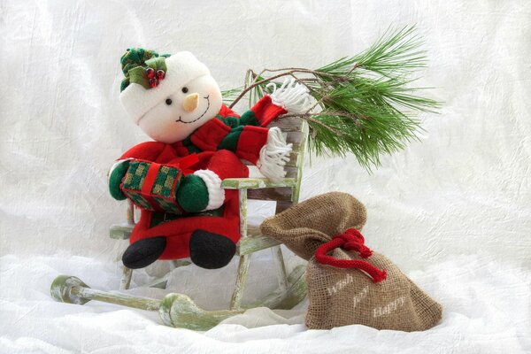 A snowman holds a pine branch