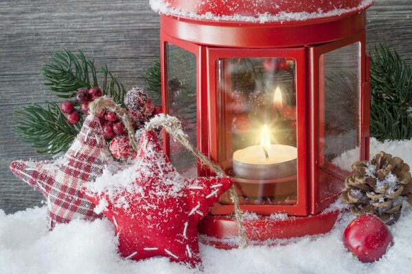 A lamp with candles in the snow and Christmas toys