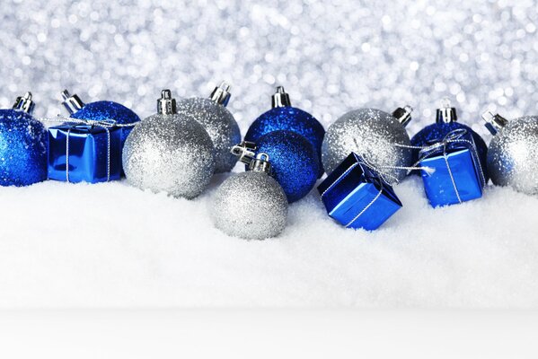 White and blue shiny Christmas decorations are lying in the snow