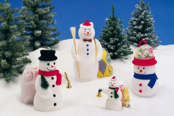 A family of snowmen in the snow on the background of Christmas trees