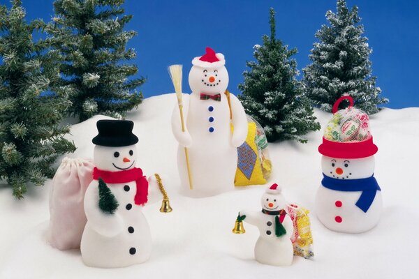 Familia de muñecos de nieve en la nieve en el fondo de los árboles de Navidad