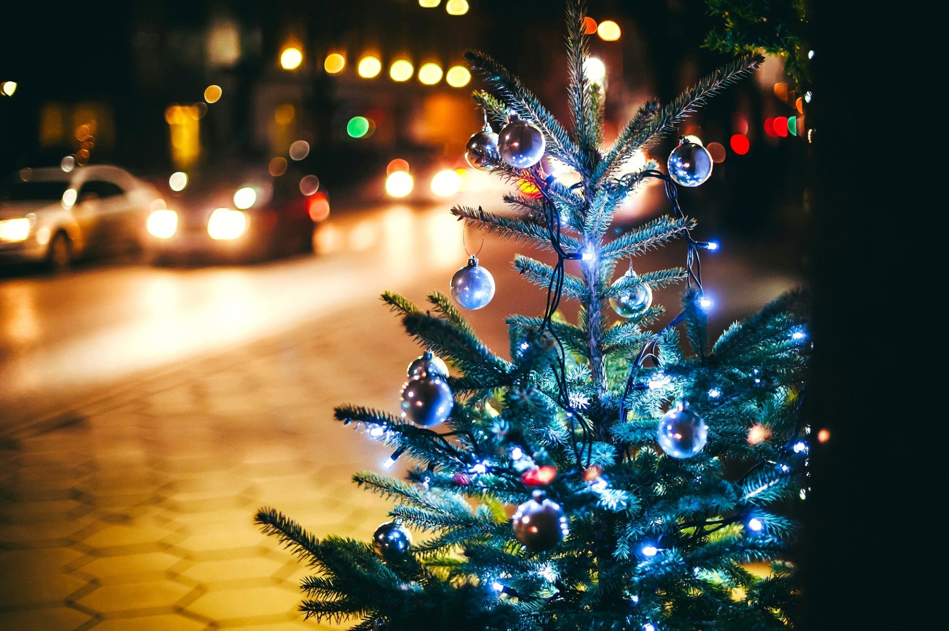 świerk girlandy choinkowe gałęzie kulki ozdoby choinkowe światła bokeh miasto noc ulica droga samochody chodnik zimowe wakacje nowy rok boże narodzenie