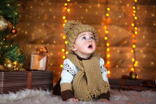 A child on a New Year s background in a hat and scarf looks up