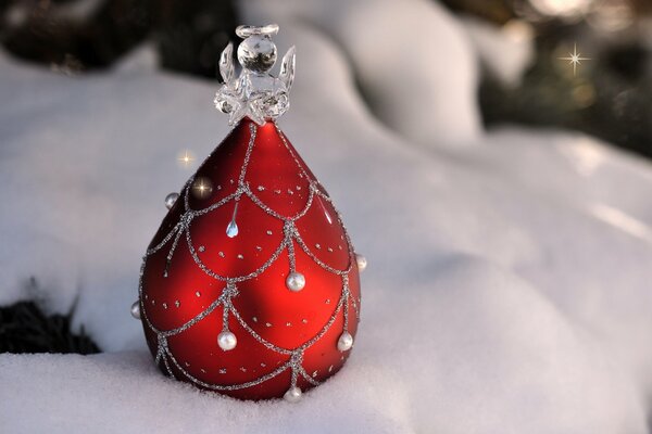 Giocattolo di Natale rosso con un angelo sulla neve