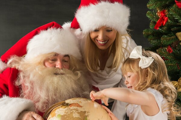 Le père Noël tient un Globe que la femme et la fille considèrent