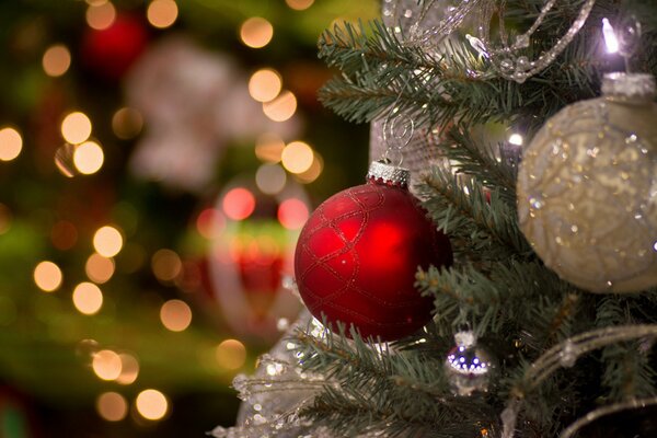 Dos bolas de árbol de Navidad cuelgan del árbol de Navidad contra el fondo de las luces
