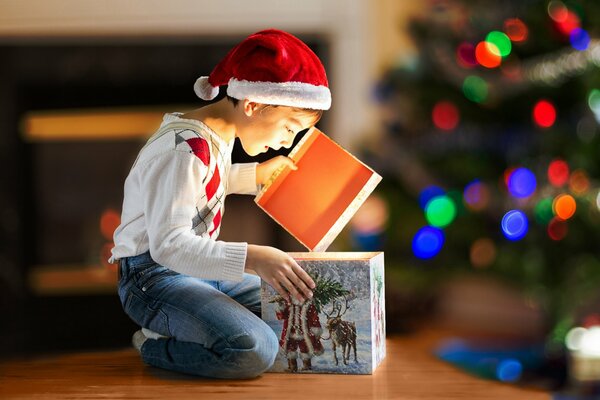 Un niño abre su regalo entre las luces de Navidad