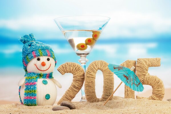 Цифры 2015 на пляже в окружении снеговика и бокала мартини с зонтиком