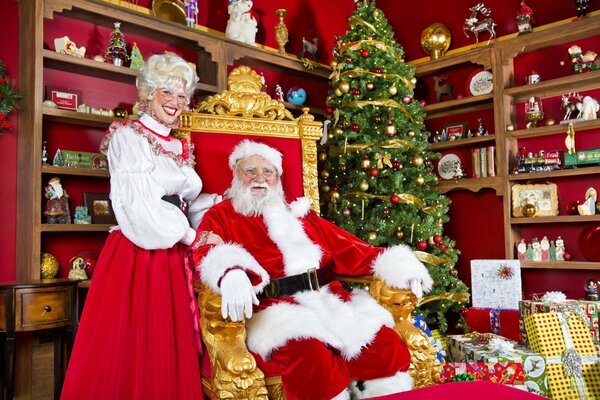 Święty Mikołaj na czerwonym tronie z choinką prezenty
