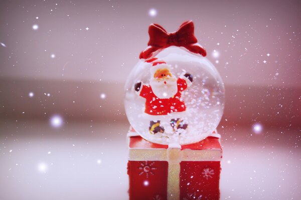 Una bola de Navidad divertida con Papá Noel se encuentra en una Caja roja