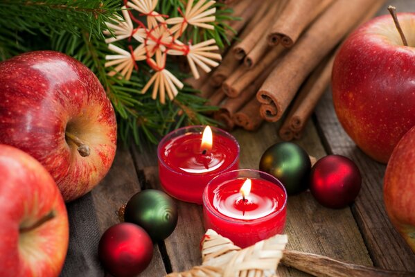 Rote Kerzen mit Weihnachtssymbolen, Zimt und Christbaumschmuck