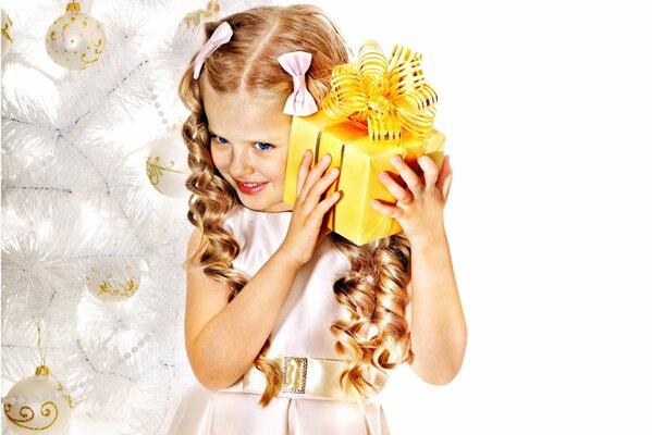 Fille avec des boucles et des arcs avec un cadeau de Noël